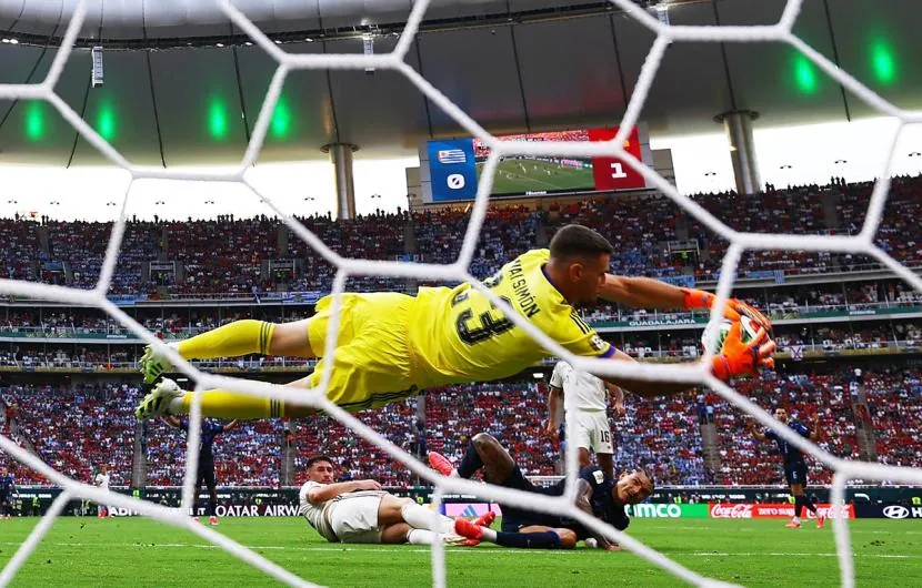Spain's goalkeeper Unai Simon saves a shot from Uruguay's Darwin Nunez.