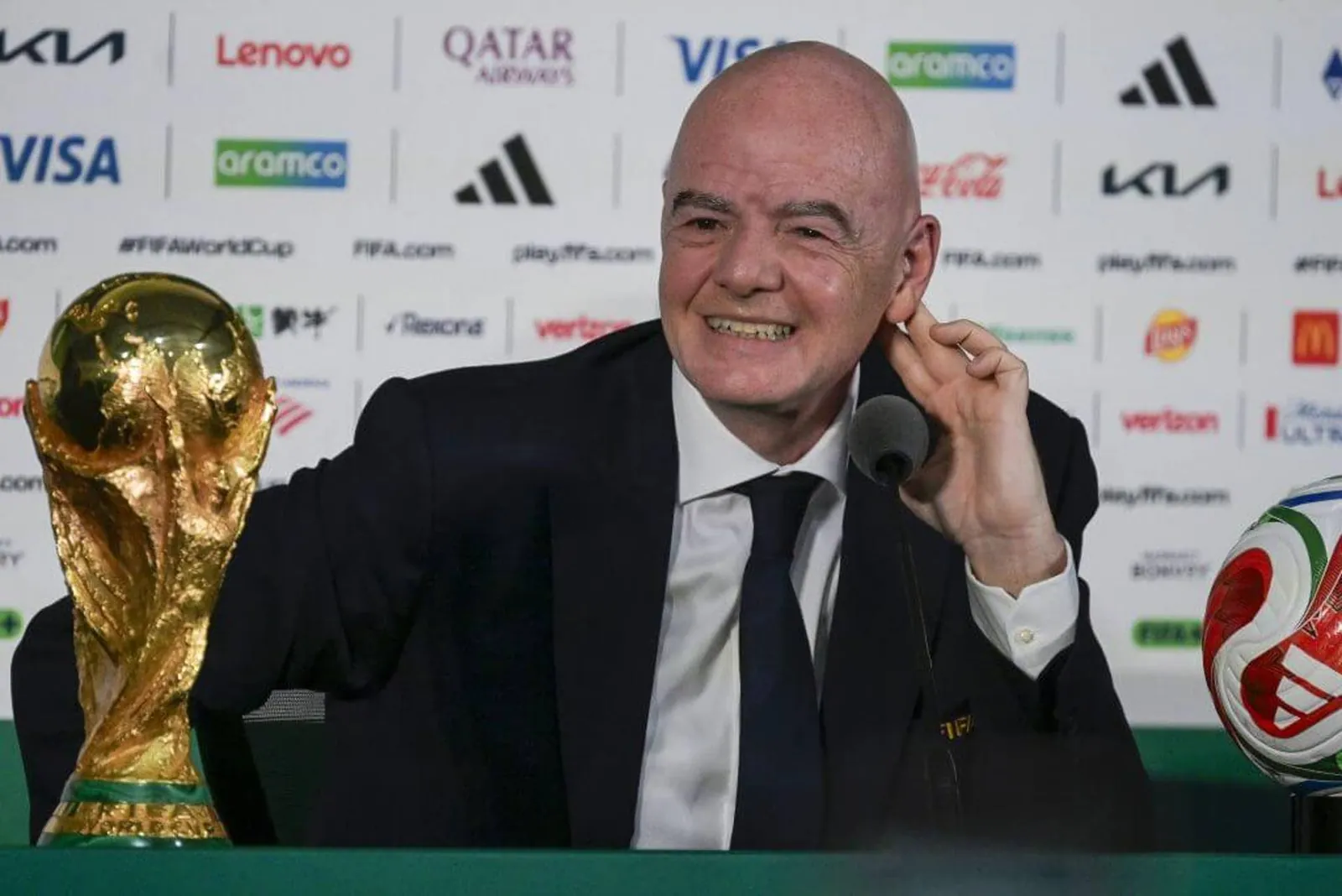 FIFA president Gianni Infantino sitting beside the World Cup trophy at a press conference