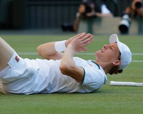 Jannik Sinner lies on the grass after his victory